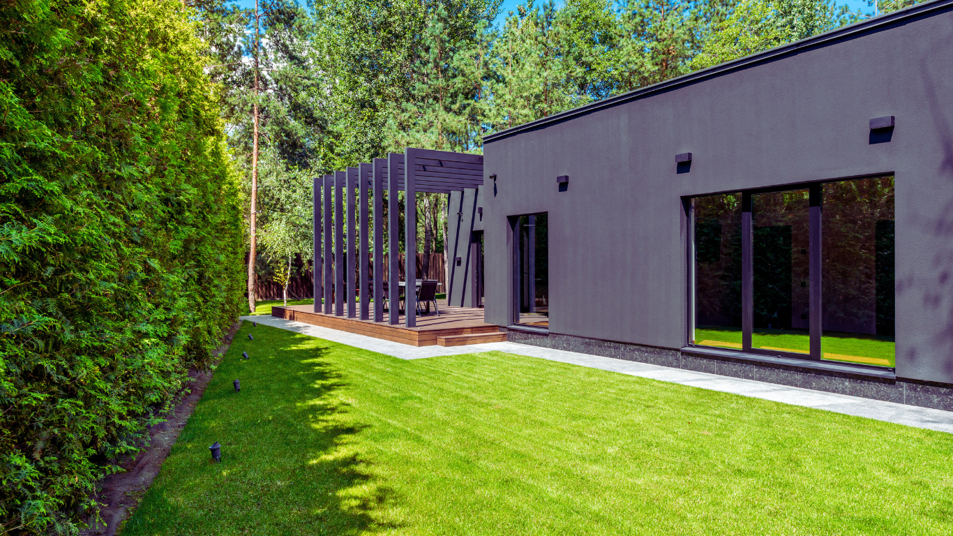 How Regular Irrigation Maintenance Can Keep Your Business Green Modern commercial building with a sleek black exterior and well-maintained green lawn, showcasing the benefits of regular irrigation maintenance for businesses.